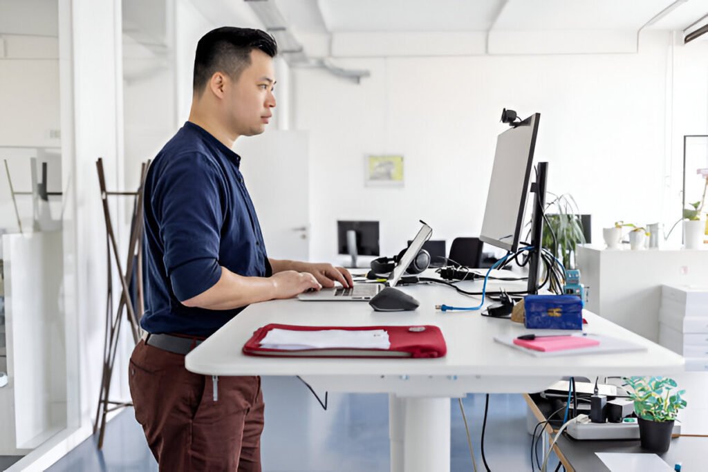 Businessman working at ergonomic standing desk in office. Male employee working on computer at his workplace illustrating an ergonomics home office setup