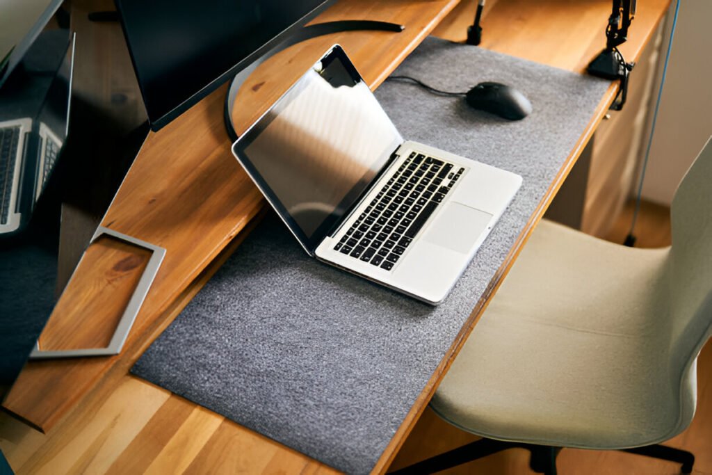 High-angle view of a modern home office desk setup featuring a laptop, external monitors, a wireless mouse, and a comfortable chair, creating the best home office setup for productivity